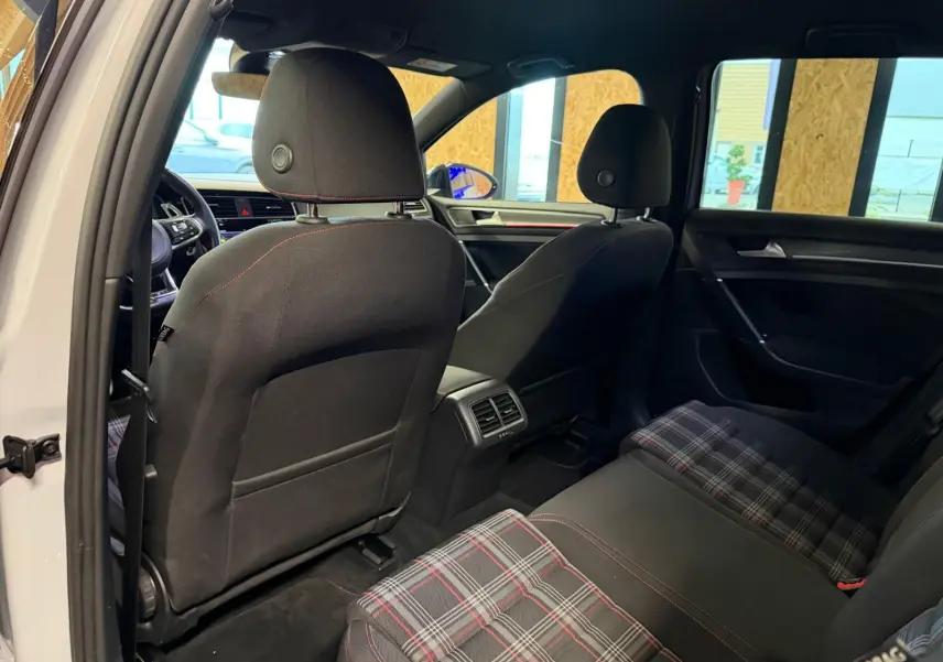 Vue rapprochée du volant sport noir avec surpiqûres rouges et tableau de bord numérique de la Volkswagen Golf GTI Performance.