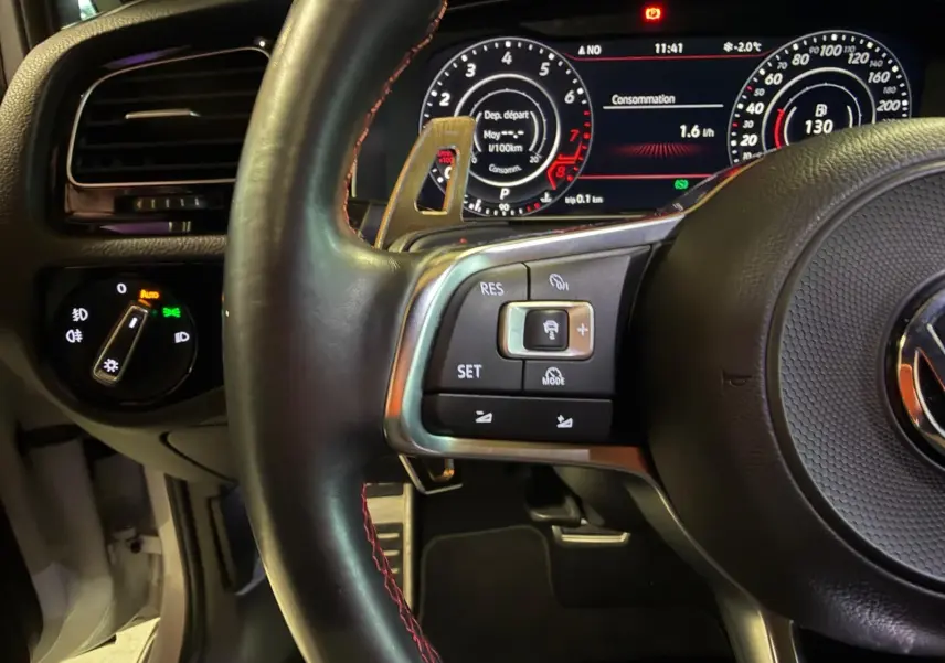 Vue intérieure de la porte arrière gauche ouverte d’une Volkswagen Golf GTI Performance grise, avec garniture noire et poignée argentée.