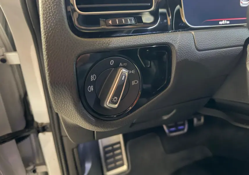 Vue intérieure côté passager de la Volkswagen Golf GTI 2018 avec sièges sport à motif tartan et console centrale noire.