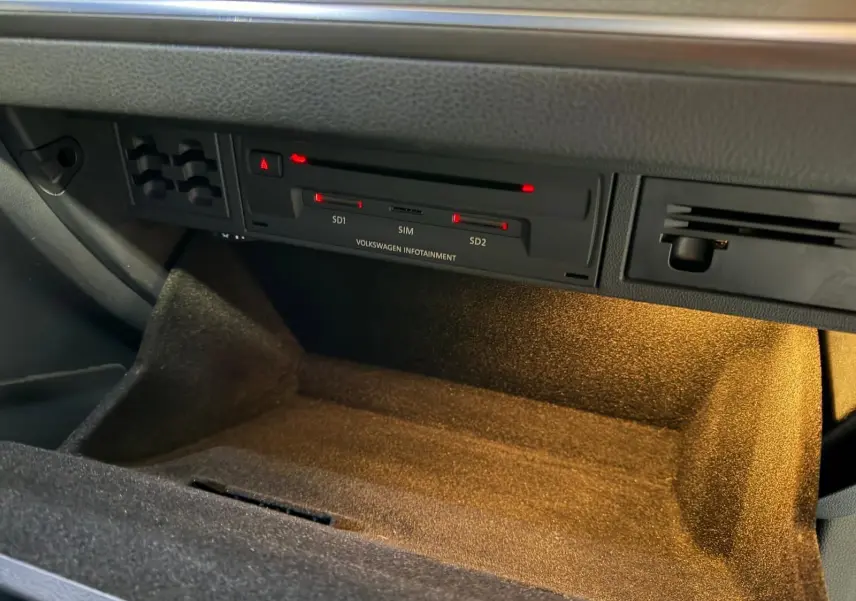 Gros plan avant gauche d'une Volkswagen Golf GTI Performance gris clair avec phares LED allumés et logo GTI rouge.