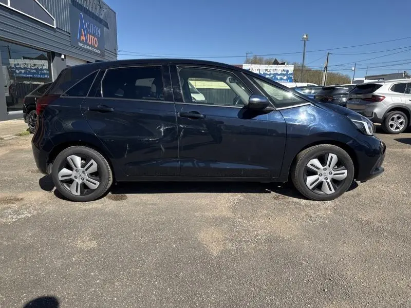 Profil latéral droit de la Honda Jazz 1.5 i-MMD bleu nuit nacré, avec jantes alu et vitres arrière surteintées.