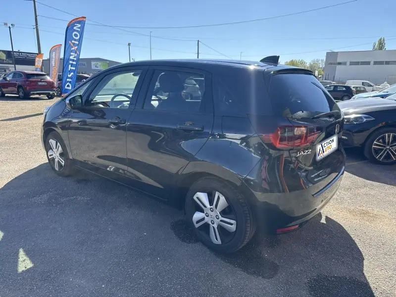 Vue 3/4 arrière droite d'une Honda Jazz 1.5 i-MMD bleu nuit nacré avec vitres arrière surteintées et jantes alu.