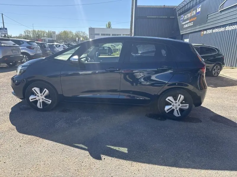 Vue latérale droite d'une Honda Jazz 2021 bleu nuit nacré garée en extérieur, avec jantes alliage visibles.