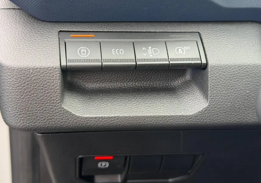 Détail des commandes de tableau de bord noir du Dacia Duster 2025, boutons ECO et aide au démarrage visibles.