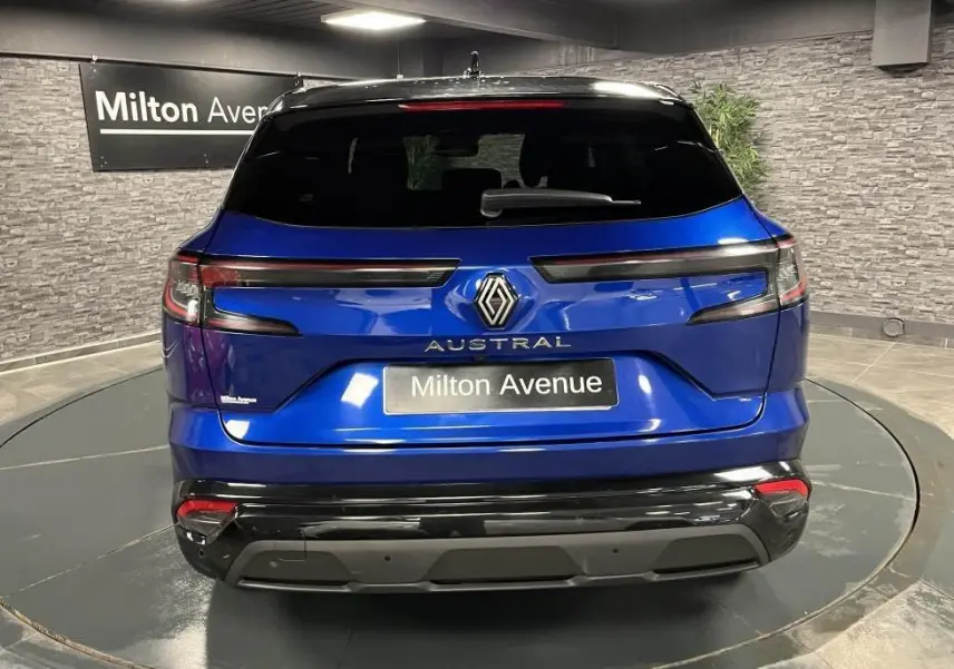 Vue arrière d'un Renault Austral bleu avec toit noir et hayon motorisé dans un showroom intérieur.