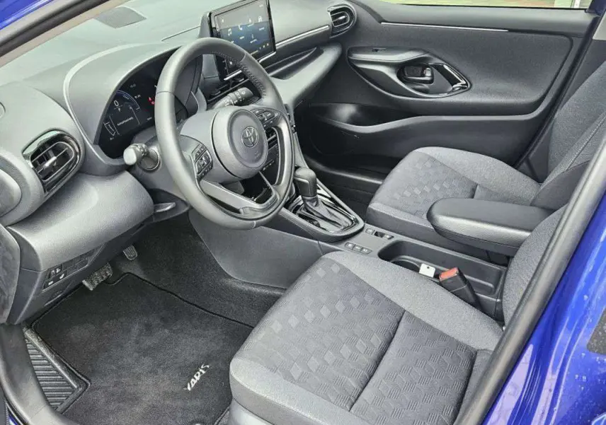 Intérieur avant droit de la Toyota Yaris 1.5 Hybrid 116 BVA Design 2025 avec sellerie grise et tableau de bord moderne.