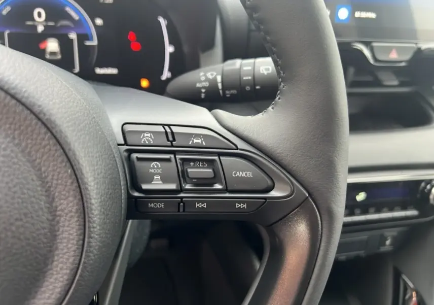 Vue rapprochée du volant de la Toyota Yaris 1.5 Hybrid 116 BVA Design 2025, montrant les commandes de régulateur de vitesse.