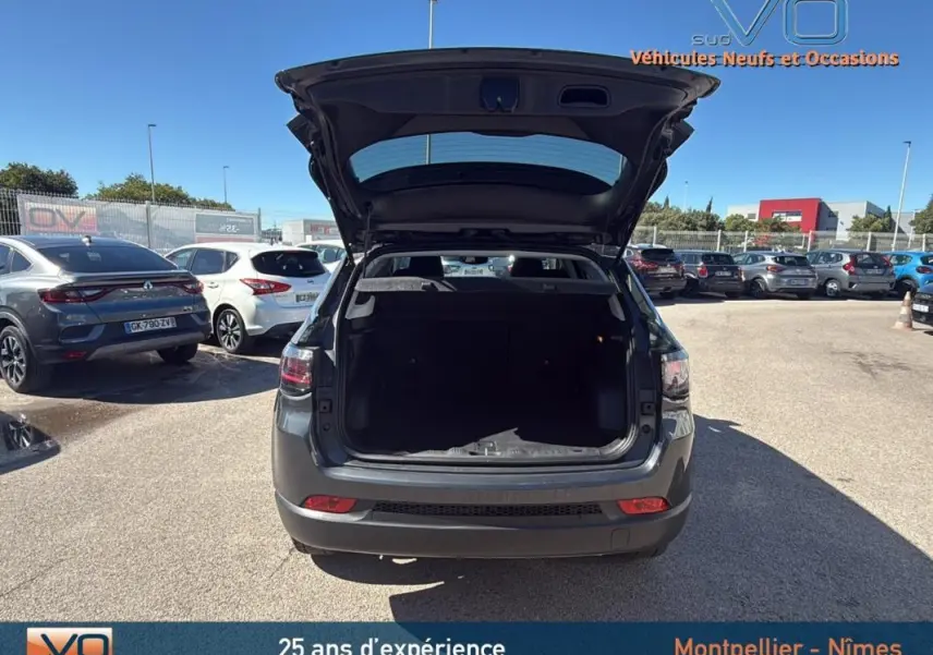 Vue arrière d’un Jeep Compass gris 2023 avec coffre ouvert, montrant l’espace de chargement vide et les feux arrière LED.