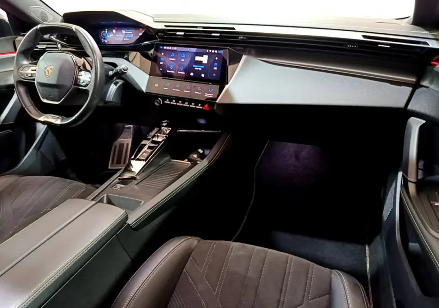 Intérieur Peugeot 308 PHEV 180 GT 2022 vu côté passager, tableau de bord moderne avec écran tactile et volant cuir.