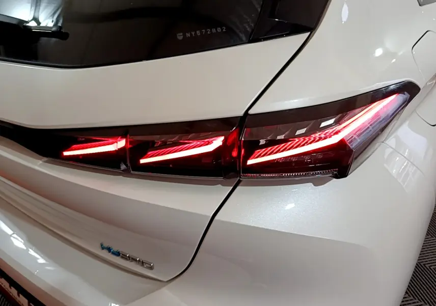 Gros plan sur le feu arrière droit allumé d'une Peugeot 308 PHEV 180 E-EAT8 GT blanche de 2022.