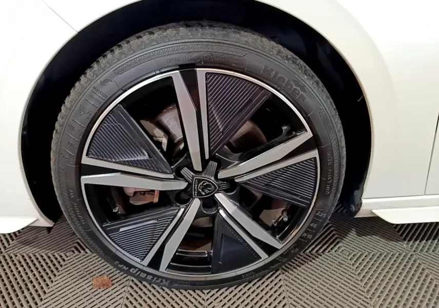 Gros plan sur la roue avant gauche de la Peugeot 308 PHEV 180 E-EAT8 GT blanche avec jante noire et argentée design moderne.