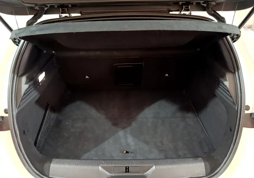 Coffre ouvert vu de l'arrière d'une Peugeot 308 PHEV 180 E-EAT8 GT blanche, intérieur noir et espace de rangement.