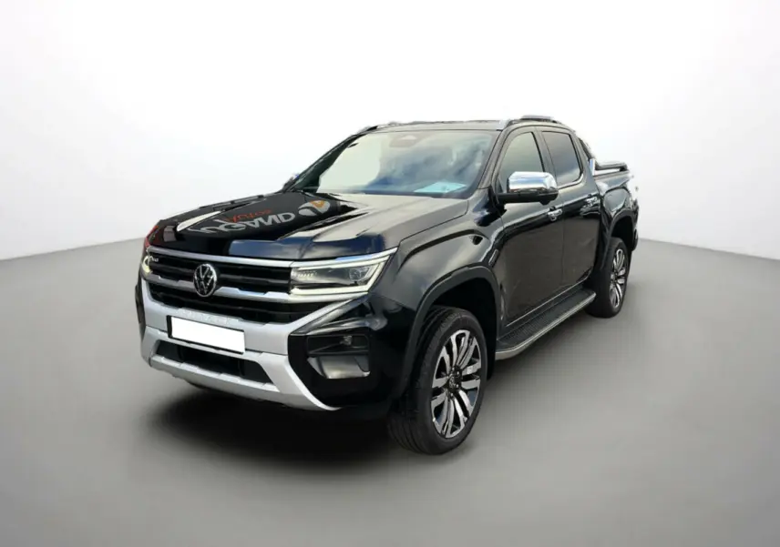 Volkswagen Amarok V6 noir en 3/4 avant droit avec jantes alu 21 pouces et barres de toit visibles.