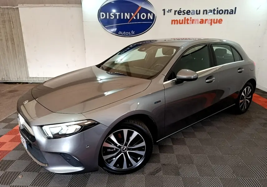 Vue 3/4 avant droite d'une Mercedes Classe A A 250 e Business Line grise avec jantes alliage et phares LED allumés.