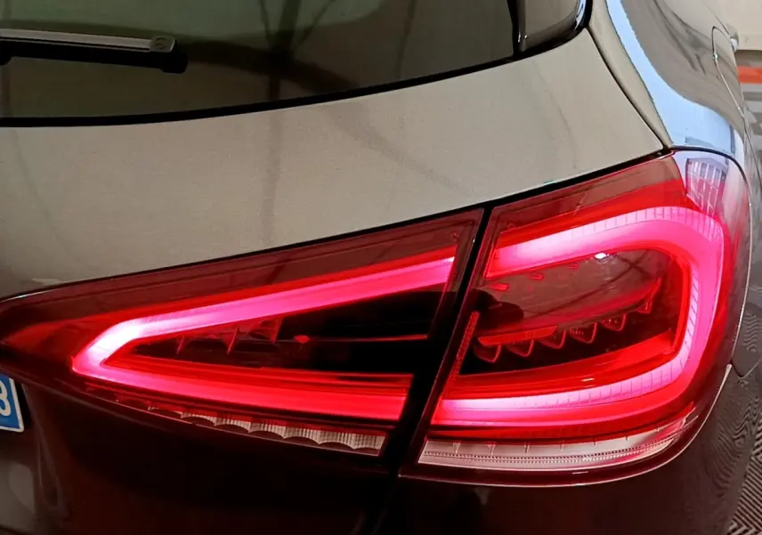 Gros plan sur le feu arrière droit rouge allumé d’une Mercedes Classe A hybride rechargeable couleur sombre.