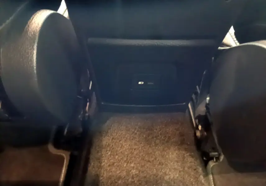 Vue intérieure arrière centrée sur la moquette et la partie inférieure des sièges avant noirs d'une Mercedes Classe A hybride.