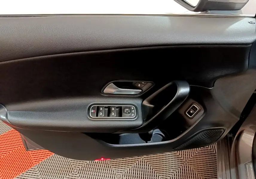 Vue intérieure du panneau de porte côté conducteur noir d'une Mercedes Classe A 250 e Business Line 2020 avec commandes électriques.