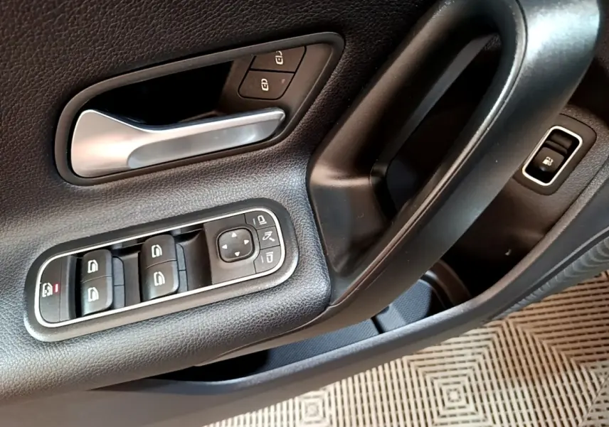 Gros plan sur la commande des vitres et la poignée de porte intérieure noire de la Mercedes Classe A 250 e Business Line 2020.