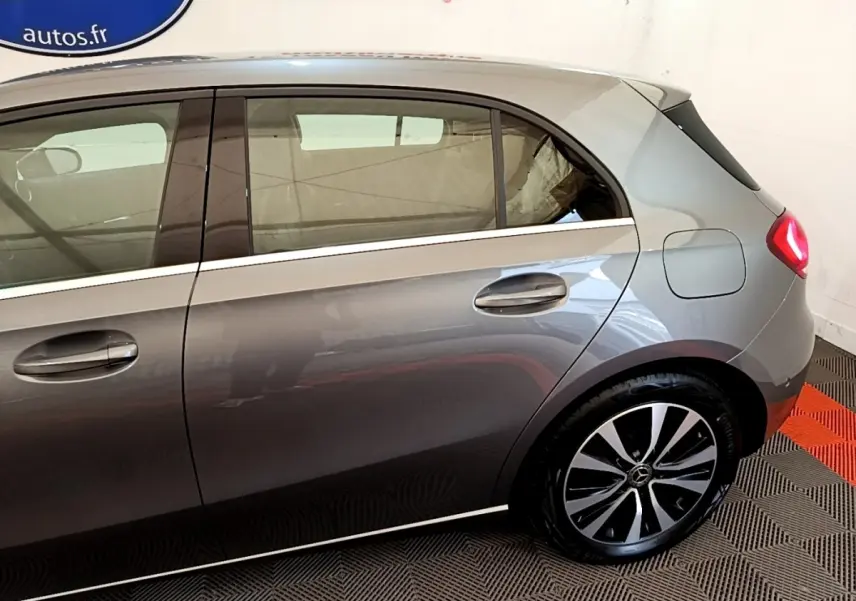 Vue latérale droite d'une Mercedes Classe A hybride rechargeable gris métallisé avec jantes distinctives et feux arrière allumés.