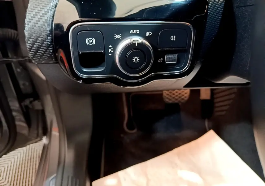 Vue rapprochée du panneau de commande des phares et frein à main électrique dans une Mercedes Classe A noire.