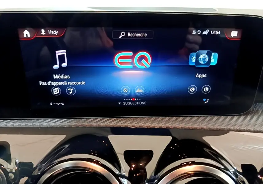 Écran tactile central affichant le menu EQ sur tableau de bord noir et garniture effet carbone d'une Mercedes Classe A hybride rechargeable.