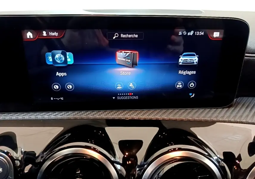 Gros plan sur l’écran tactile central et les aérateurs ronds noirs du tableau de bord de la Mercedes Classe A hybride.