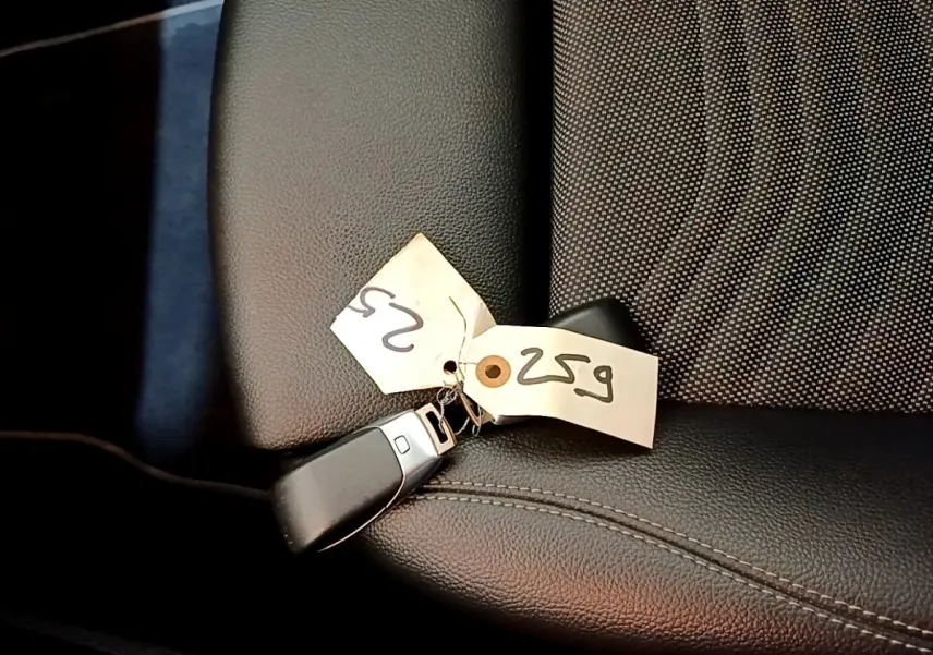 Gros plan sur la clé noire avec étiquette posée sur le siège avant en cuir noir de la Mercedes Classe A hybride rechargeable.