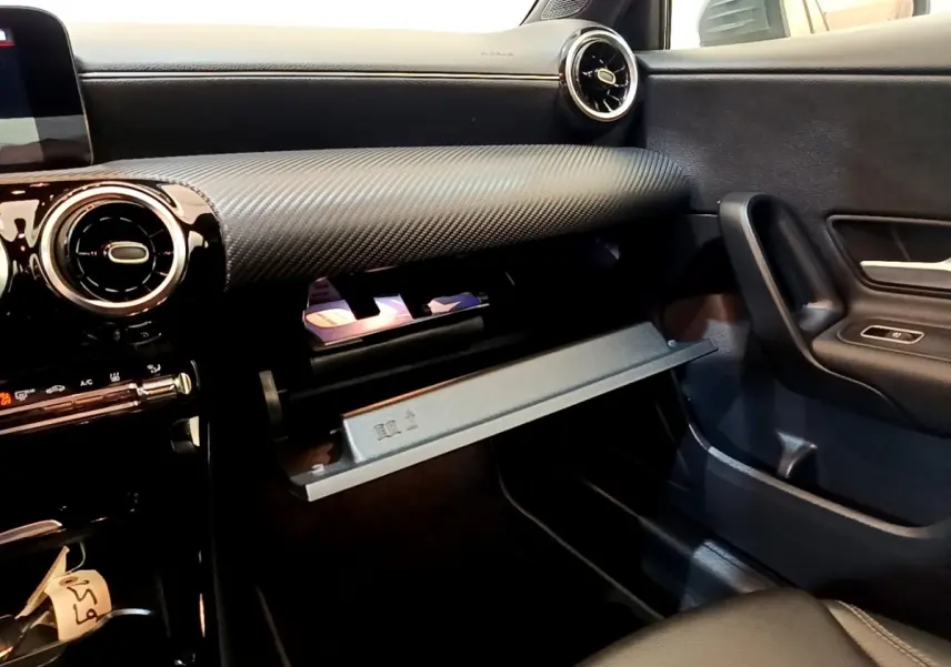 Vue intérieure côté passager de la Mercedes Classe A 250 e Business Line 2020, tableau de bord noir avec boîte à gants ouverte.