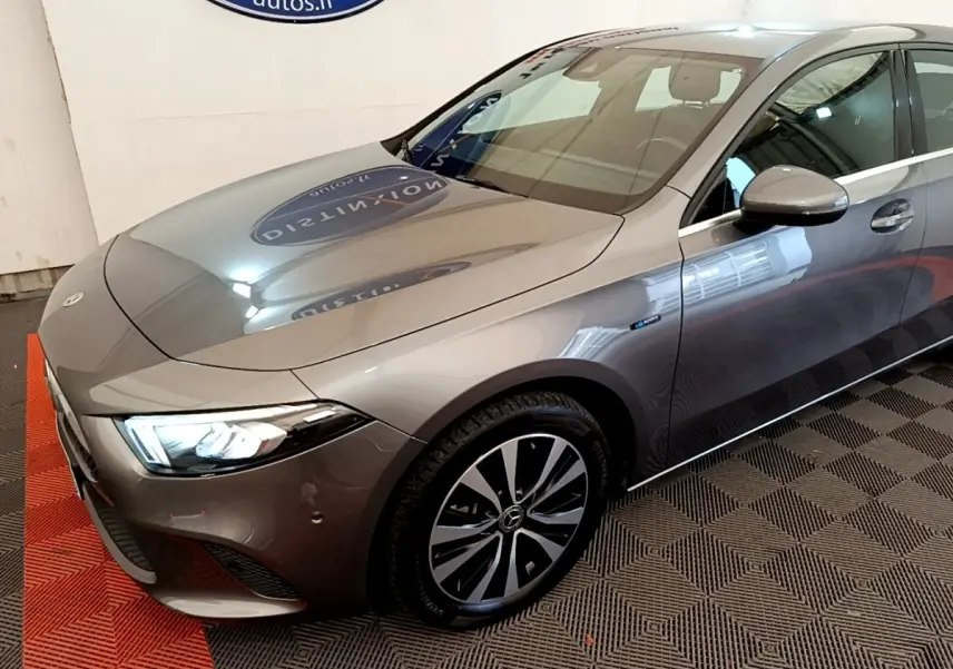 Mercedes Classe A 250 e Business Line gris métallisé vue 3/4 avant droit avec phares LED allumés et jantes distinctives.