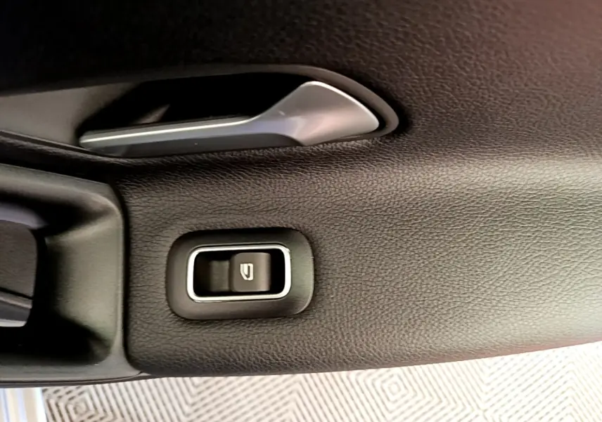 Gros plan sur la poignée intérieure et bouton de verrouillage de porte côté gauche, garniture noire texturée Mercedes Classe A 250 e.