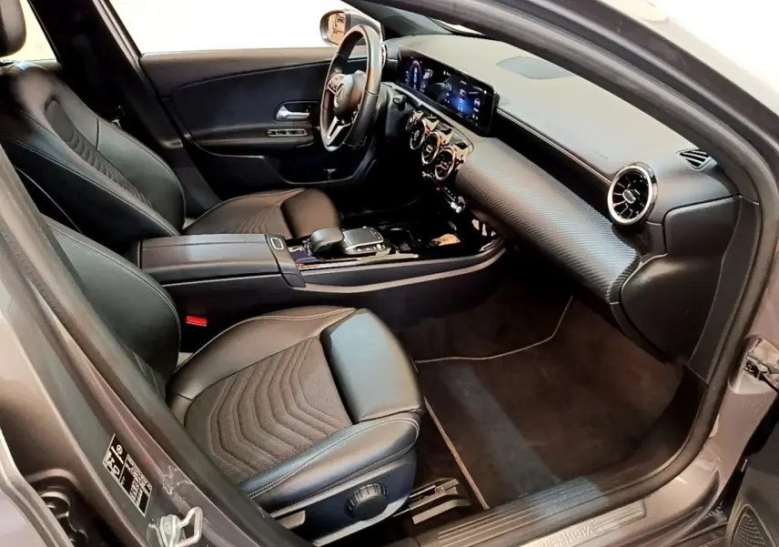 Vue intérieure côté conducteur de la Mercedes Classe A 250 e Business Line 2020 avec sièges cuir noirs et tableau de bord digital.