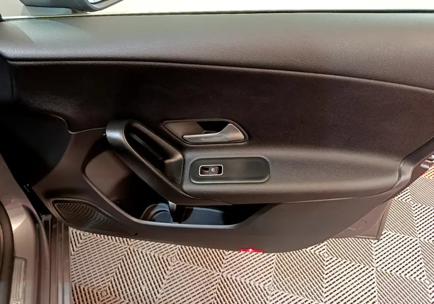 Vue intérieure du panneau de porte côté gauche noir de la Mercedes Classe A 250 e Business Line 2020 avec poignée et commande de vitre électrique.