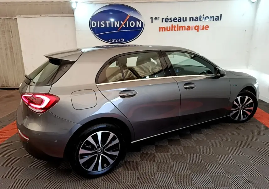 Vue 3/4 arrière droite d'une Mercedes Classe A A 250 e Business Line grise métallisée en intérieur showroom.
