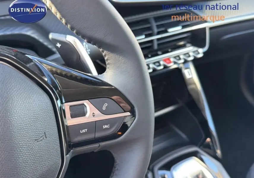 Gros plan sur le volant cuir de la Peugeot 208 gris, avec commandes intégrées et palettes au volant visibles.