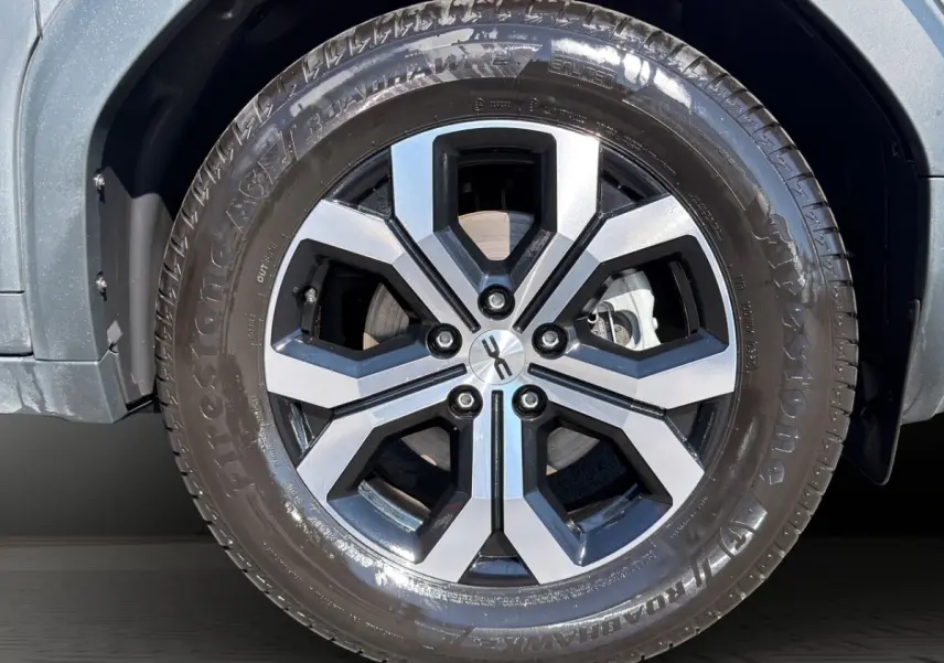 Gros plan sur la roue avant droite du Dacia Duster gris foncé avec jante alliage à design hexagonal.