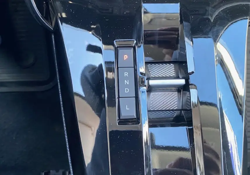 Gros plan sur la console centrale noire brillante du Citroën C3 Aircross 1.2i Hybride avec sélecteur de boîte automatique.