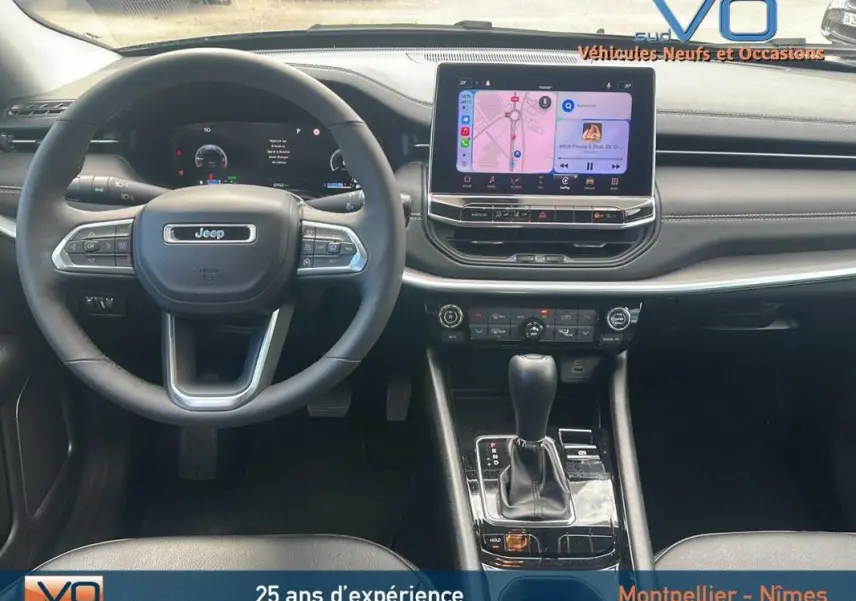 Vue intérieure centrée sur le volant et l'écran tactile du Jeep Compass 2023, finition Limited, avec console et commandes visibles.