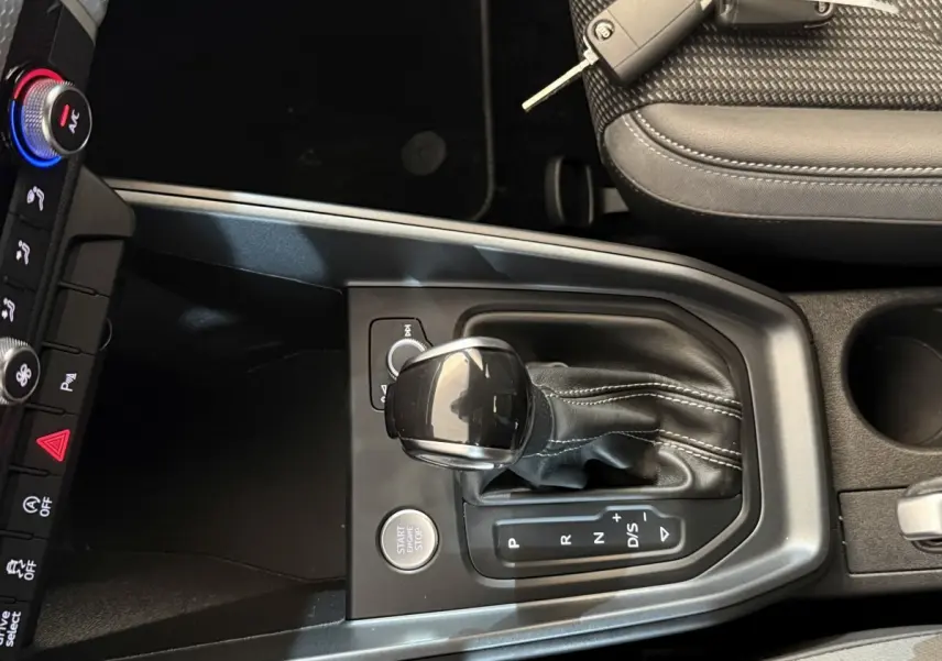 Vue rapprochée de la console centrale de l'Audi A1 gris foncé 2020, avec levier de vitesses automatique et bouton start/stop.
