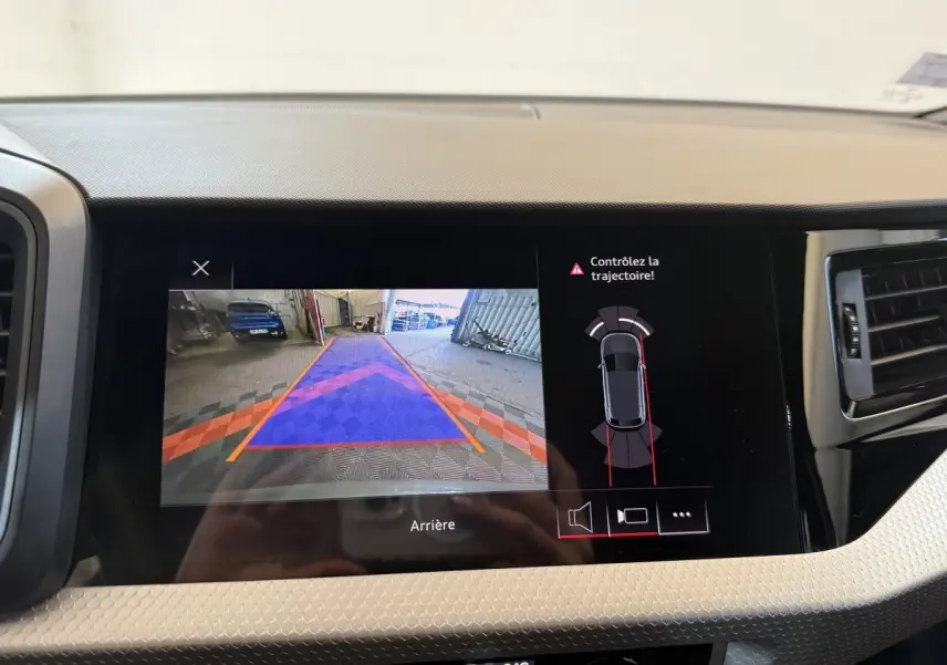 Écran central de l'Audi A1 2020 affichant la caméra de recul et l'alerte trajectoire en intérieur gris clair.
