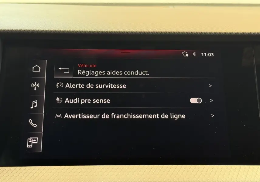 Écran tactile intérieur de l'Audi A1 2020 affichant les réglages d'aides à la conduite sur fond noir.