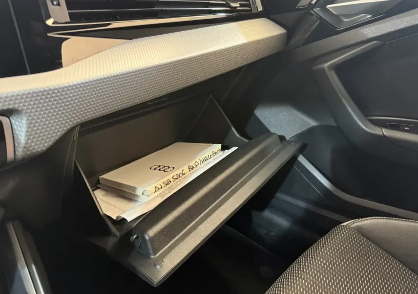 Gros plan sur la boîte à gants ouverte côté passager de l'Audi A1 1.5 TFSI 2020 avec documents à l'intérieur.