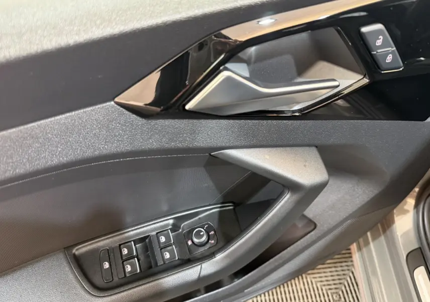 Détail de la porte côté conducteur d'une Audi A1 gris foncé avec commandes de vitres et rétroviseurs électriques.