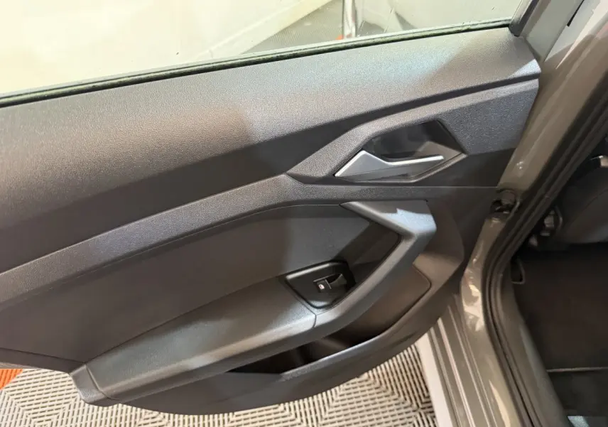 Gros plan sur la porte côté gauche gris foncé de l'Audi A1 1.5 TFSI S line avec poignée intérieure argentée.