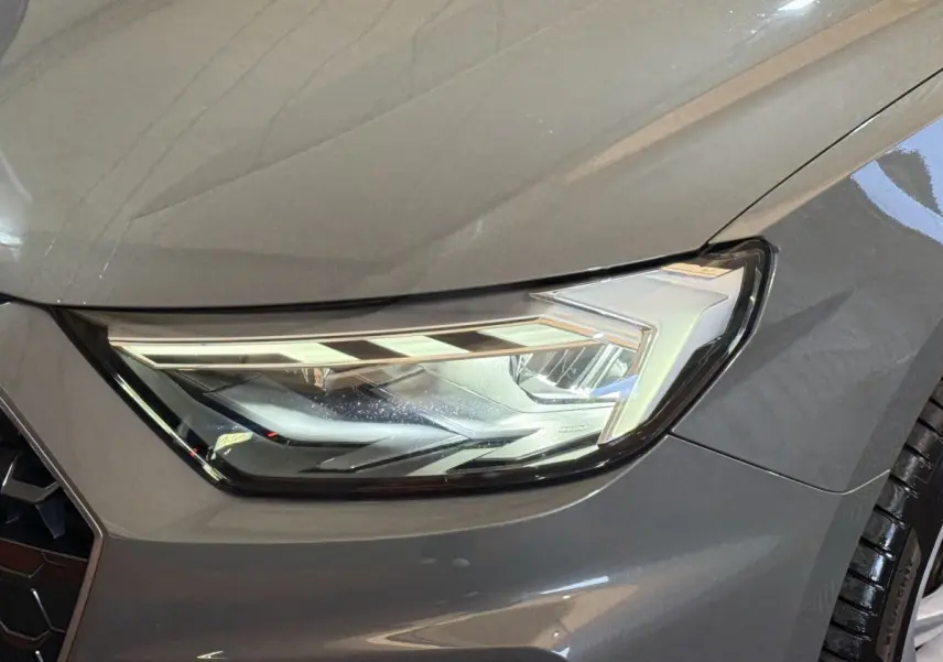 Gros plan sur le phare avant droit d'une Audi A1 gris foncé 2020, mettant en valeur son design LED moderne.