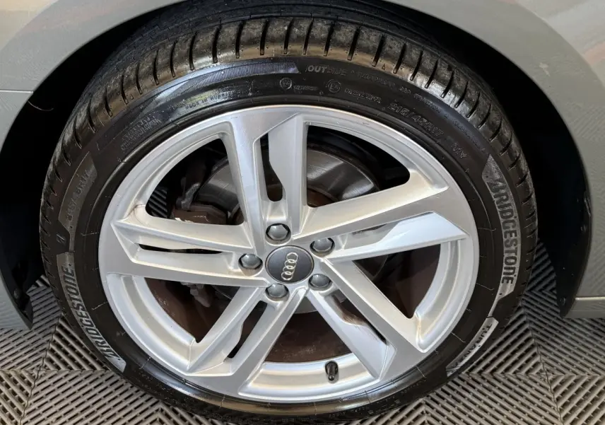 Gros plan sur la jante alliage argentée et pneu Bridgestone du côté gauche d'une Audi A1 gris foncé.