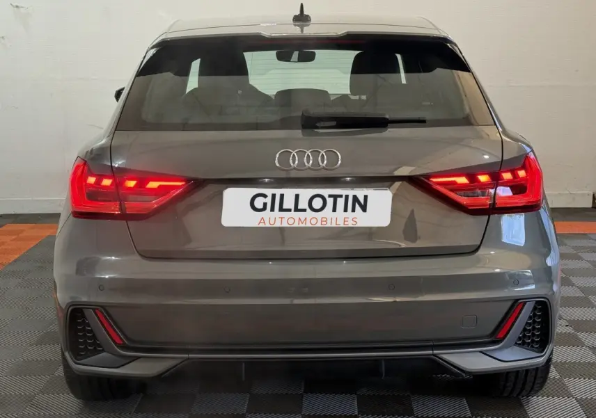 Vue arrière d'une Audi A1 1.5 TFSI S line gris foncé avec feux LED allumés et pare-chocs sport.