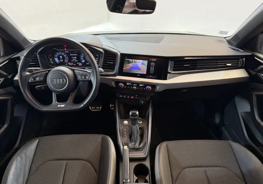 Vue intérieure avant de l'Audi A1 S line 2020, tableau de bord moderne avec écran digital et volant cuir multifonctions.