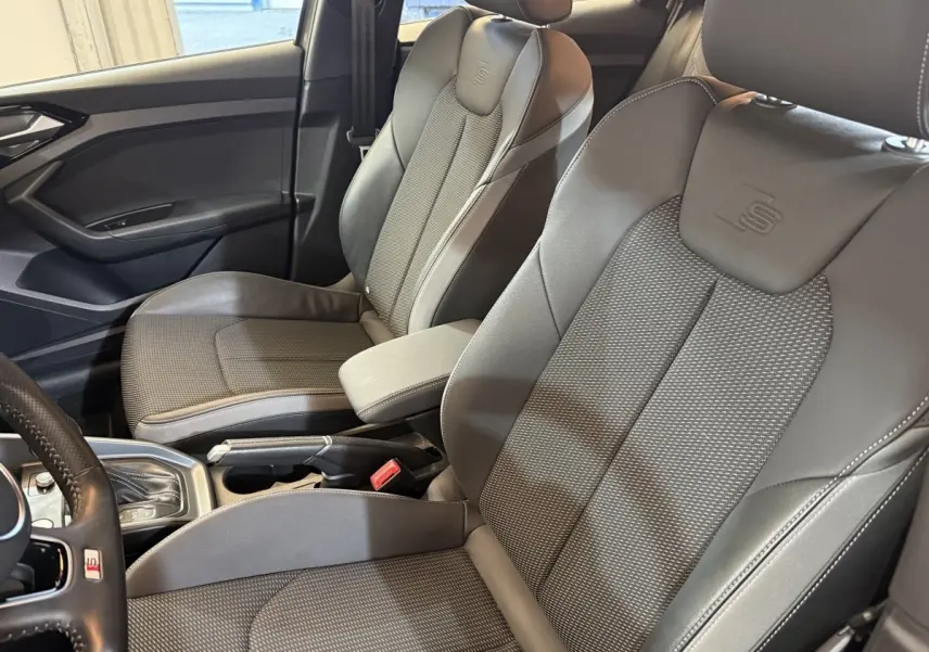 Vue intérieure côté conducteur de l'Audi A1 S line 2020, sièges sport gris avec logo S embossé sur appuie-tête.