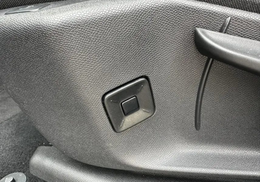 Détail du bouton de réglage manuel noir sur le côté du siège avant du Peugeot 3008 gris Artense 2024.