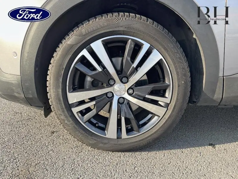 Gros plan sur la roue avant droite avec jante alu bicolore du Peugeot 5008 gris Artense, détail du pneu et passage de roue.